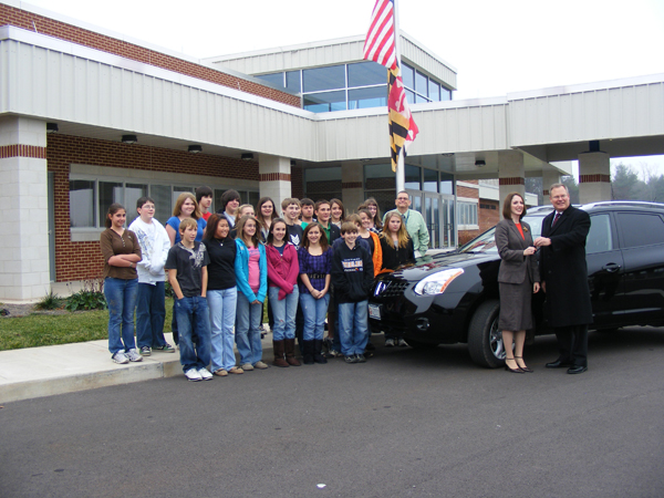 MDTOY Jennifer Rankin getting the keys to her new vehicle (2009 Nissan Rogue) from Sam Weaver, Chairman, Maryland Automobile Dealers Association. Her 8th grade algebra students and Vice Principal, Mike Pula, are pictured with her.